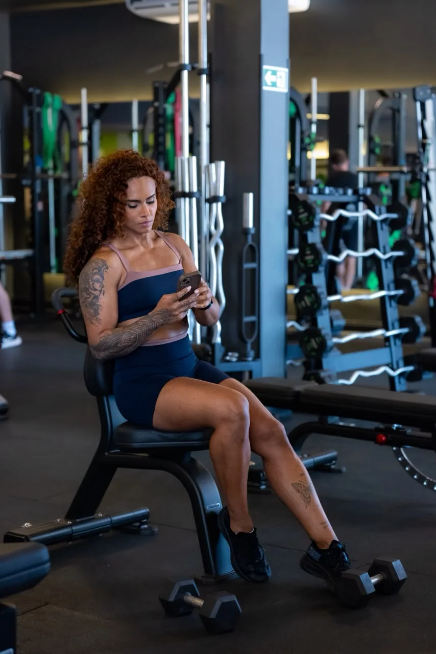 Wendy Lee sentada na academia, usando o celular